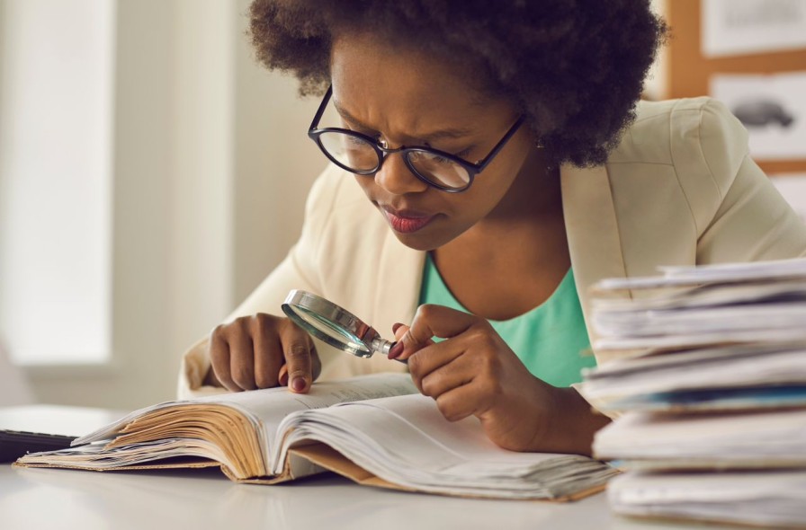 Girl reading a book with a magnifying glass